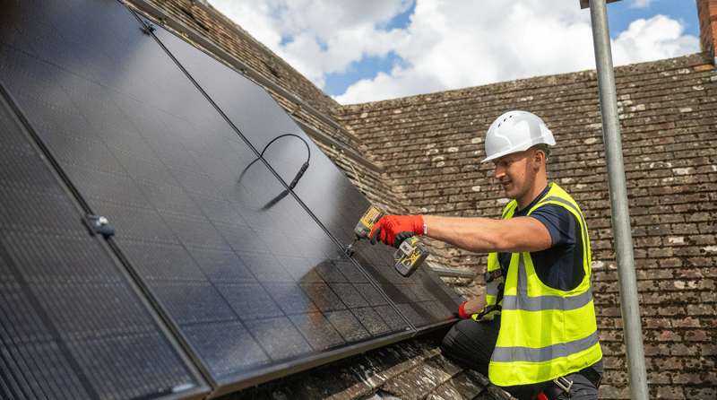 Local solar panel installer working on a residential roof in the UK